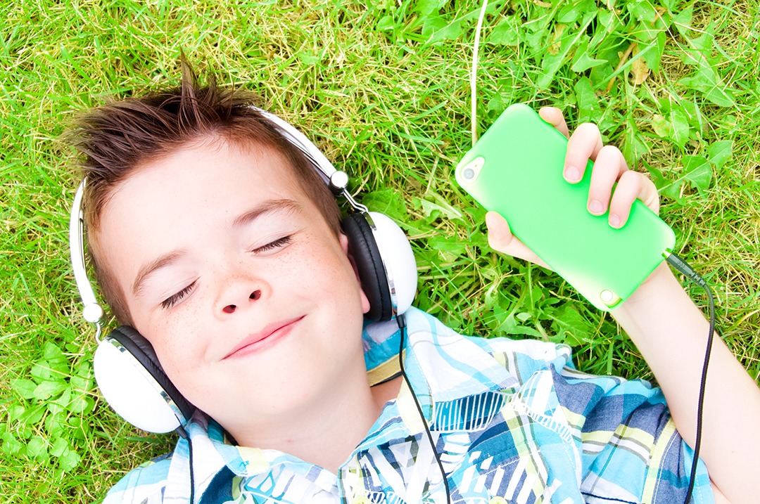 Child listening to audio in grass